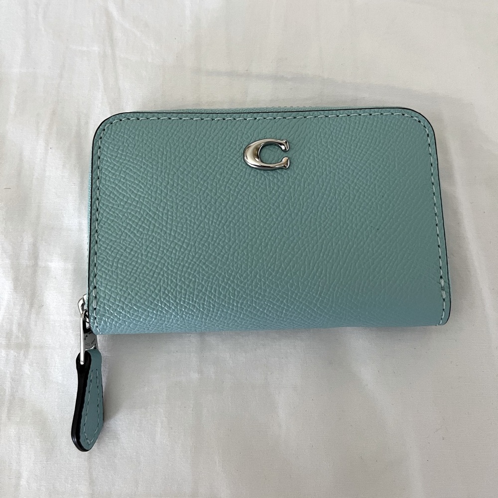 Coach zip card case in the color faded blue with silver hardware.